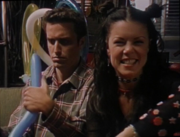 Richard, looking peevishly down at the balloon animal he's trying to make, while Molly grins at the camera