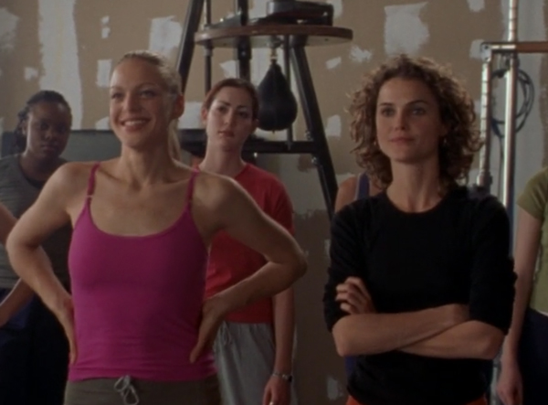 Avery, a pretty blonde, in workout clothes standing next to Felicity, who has her arms crossed