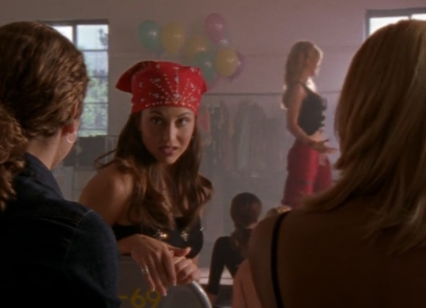 A pretty white girl with long brown hair and a red bandana over her head, shooting Felicity a mean look