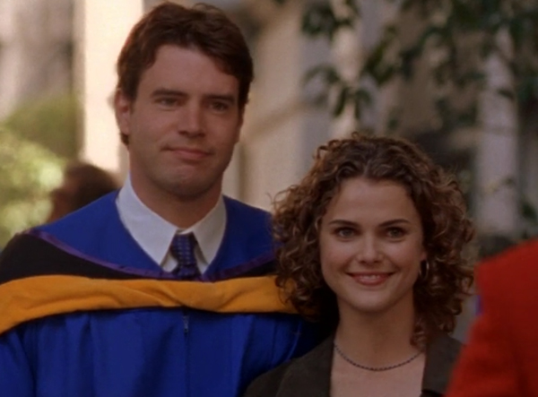 Noel, wearing a blue graduation gown, posing next to a grinning Felicity