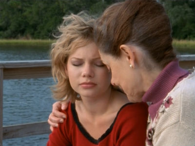 Jen and Grams sit outside on the pier, Jen looking upset and Grams holding her close, comforting her.