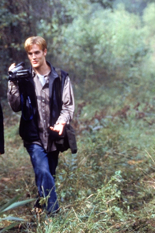 Dawson traipses through the woods holding a video camera