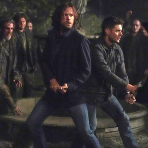 Sam and Dean Winchester surrounded by paranormal creatures in a cemetery.