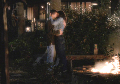 Joey and Pacey embrace and kiss in a beautiful nighttime scene, surrounded by a campfire and twinkly lights. It's pretty dreamy.