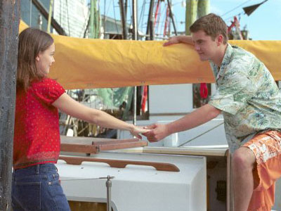 Pacey gives Joey a hand up onto his boat. The sun is shining, and they both look happy as can be.