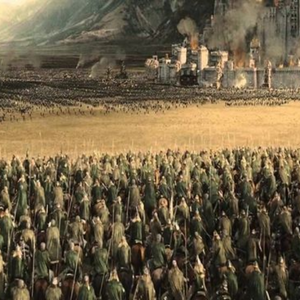 Two armies face each other across a battlefield while a city burns off to the side (from LotR).
