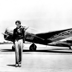 B&W image of a woman standing in front of a plane.