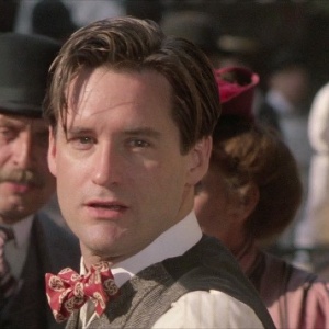 Bill Pullman, a white man with blonde hair, sporting a bowtie and vest