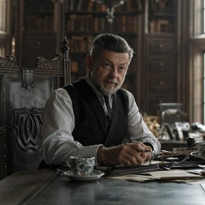 Andy Serkis, a white man with gray hair looking elegant in a vest and tie