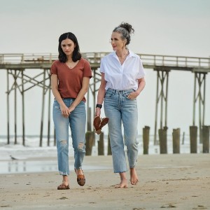 Auden and her mom, an elegant older white woman, walking on the beach