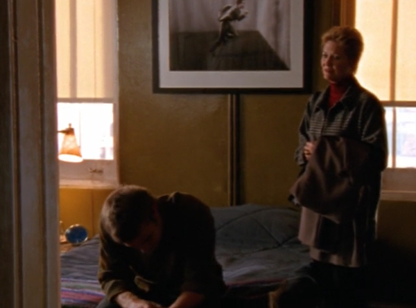 Ben's mother looks at him with concern while he sits on the edge of the bed with his head in his hands