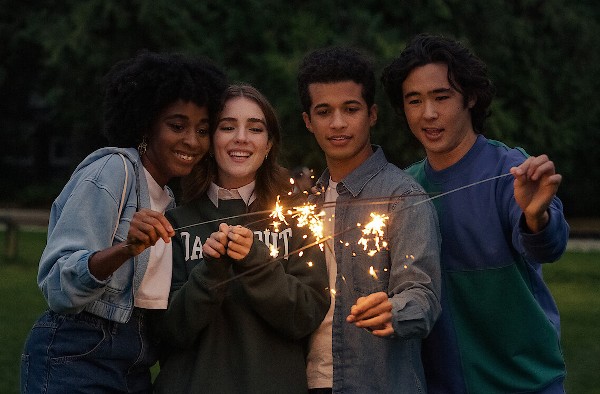 A group of teens holding sparklers: a Black girl, a white brunette, a multiracial boy, and an Asian-American boy