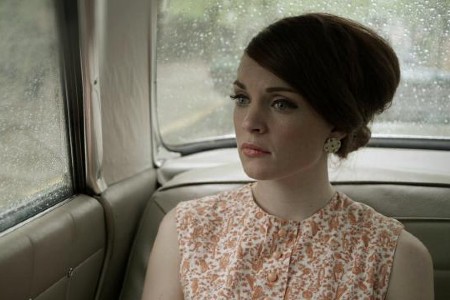 a woman with a 1950's hairstyle rides in car