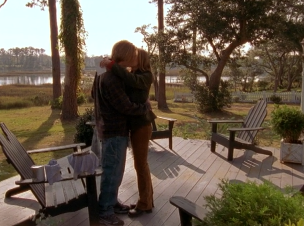 Dawson and Gretchen stand in the sunshine, kissing on Dawson's porch