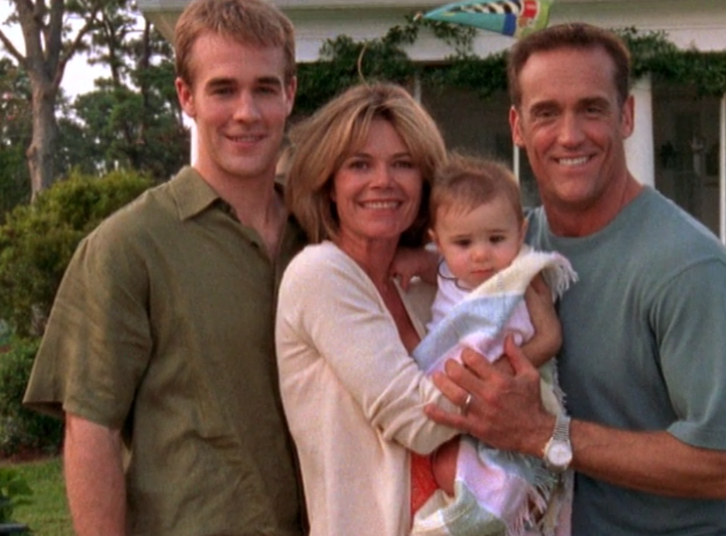 Dawson, Gail and Mitch standing together outside of their house, smiling big and holding baby Lily