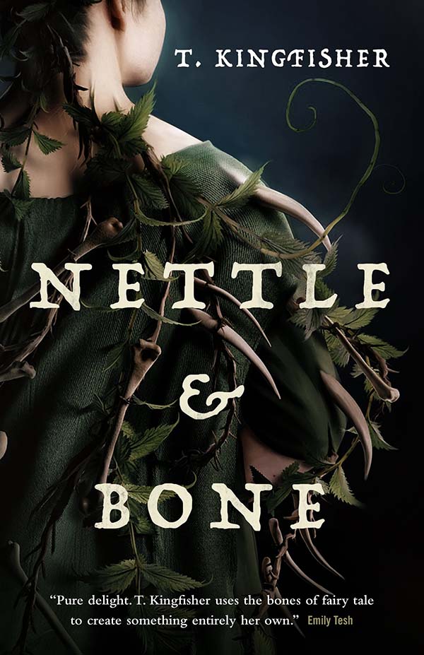 A woman’s back wearing a dark green cape covered in nettles and bones.