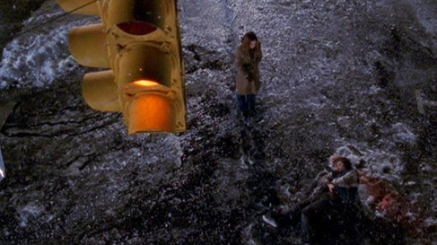 Joey's standing at a snow crossroads with a traffic light hanging above her at night