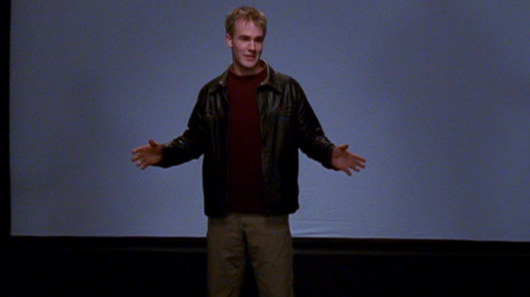 Dawson onstage in front of a movie screen, giving a talk