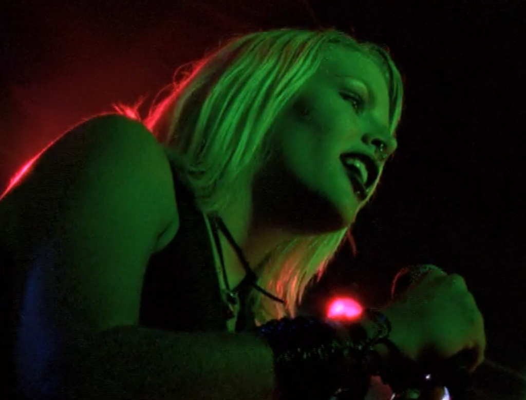 Audrey, on stage and bathed in green light, singing a punk song