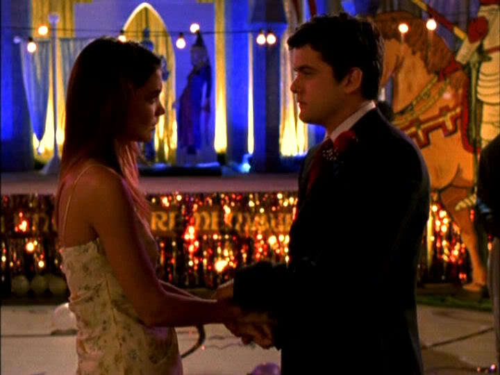 Joey and Pacey in formal attire, two adults at prom, holding each other's hands and looking into each other's eyes unhappily