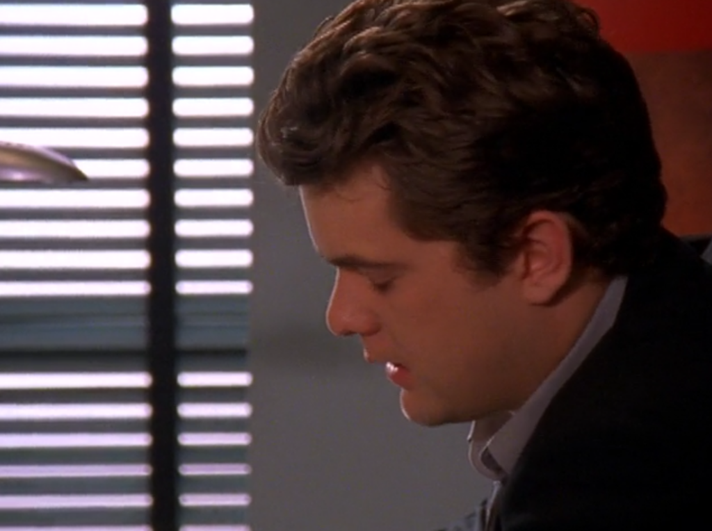 Pacey, in the office, eyes closed and head tilted downwards, looking absolutely devastated