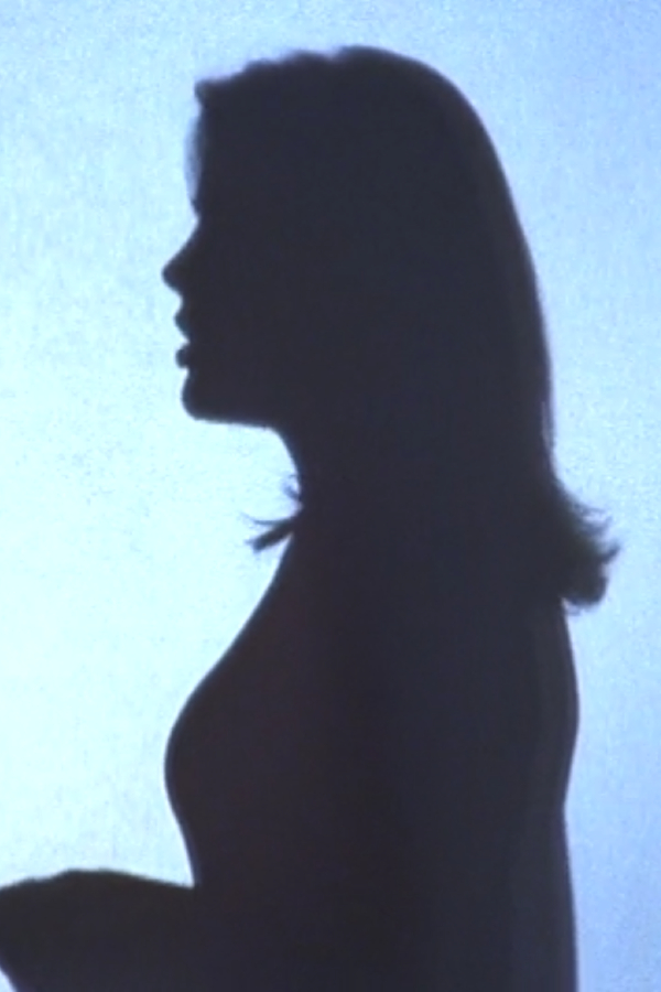 A silhouette of Audrey behind a pane of glass as she waits to go on LOVELINE