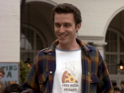 Richard, grinning in a shirt that says Free Pizza Fridays under a cartoon slice of pizza