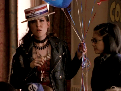 Meghan in an old-timey straw boater with "Greg for President" in red, white & blue on the brim, holding balloons and looking disgruntled