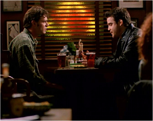 Noel and his brother sit at a booth at Epstein Bar, looking very serious