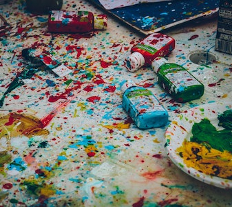 Colorful spilled paint and paint bottles on a white background