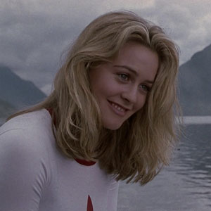 Alicia Silverstone smiles in front of a lake and mountains