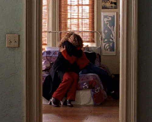 Felicity and her mom sit on the bed, embracing warmly