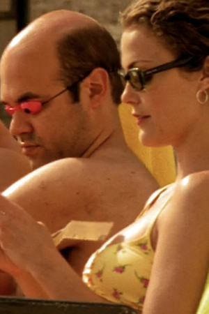 Felicity and Javier, sunning on the roof, both in bathing suits and wearing sunglasses