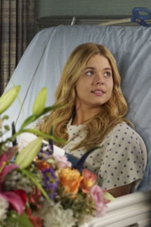 Alison lies in a hospital bed surrounded by flowers