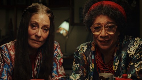 Judith Light, an older white woman with long hair, and S. Epatha Merkerson, an older Black woman with glasses, both of whom are wearing vaguely 60s clothing