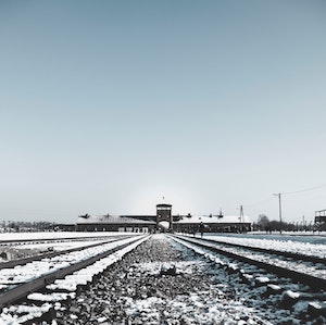 A photograph of snowy railroad tracks leading to an imposing building