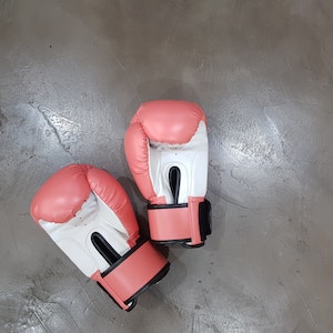 Pink and white boxing gloves on a gray concrete floor