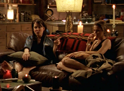 Meghan and Felicity on the couch in the loft, drinking champagne and venting to each other 