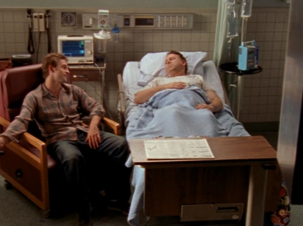 Ben sits next to his dad, who is lying in a hospital bed