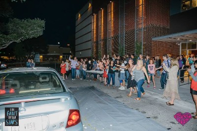 A crowd of people (mostly women) throwing eggs at a car