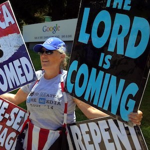 A member of Westboro Baptist Church stand with hateful signs