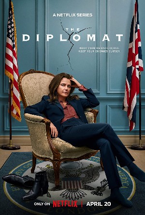 Keri Russell (a pretty white brunette) looks frustrated while sitting in a chair with American and British flags behind her