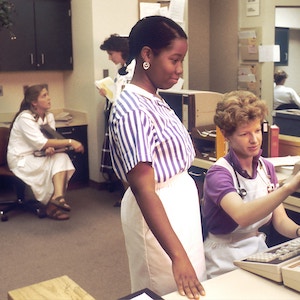 Women in 1980s clothing working in an office.