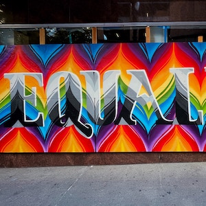 A mural of the word equal painted in vivid colors