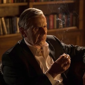 The Smoking Man from X-Files sits in a chair, smoking