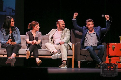 Tangi Miller, Amy Jo Johnson, and Ian Gomez sit on a couch together looking at Rob Benedict, who is miming holding a boom mic and making a funny face