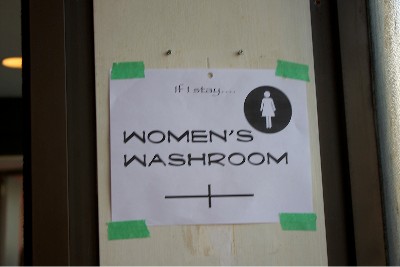 Paper sign taped to a wall that says "If I Stay... Women's Washroom"
