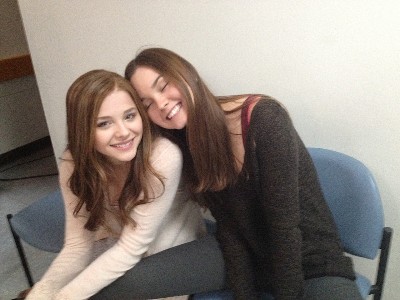 Chloe Moretz, with brown hair, with Liana Liberato smiling and leaning against her