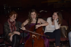 Gayle Forman and Alison Greenspan sitting next to a woman playing a cello