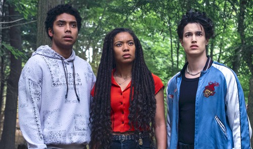 A trio of college-aged people in the forest: a handsome Black guy in a hoodie, a pretty Black girl with long braids, and a handsome Asian guy in a track jacket